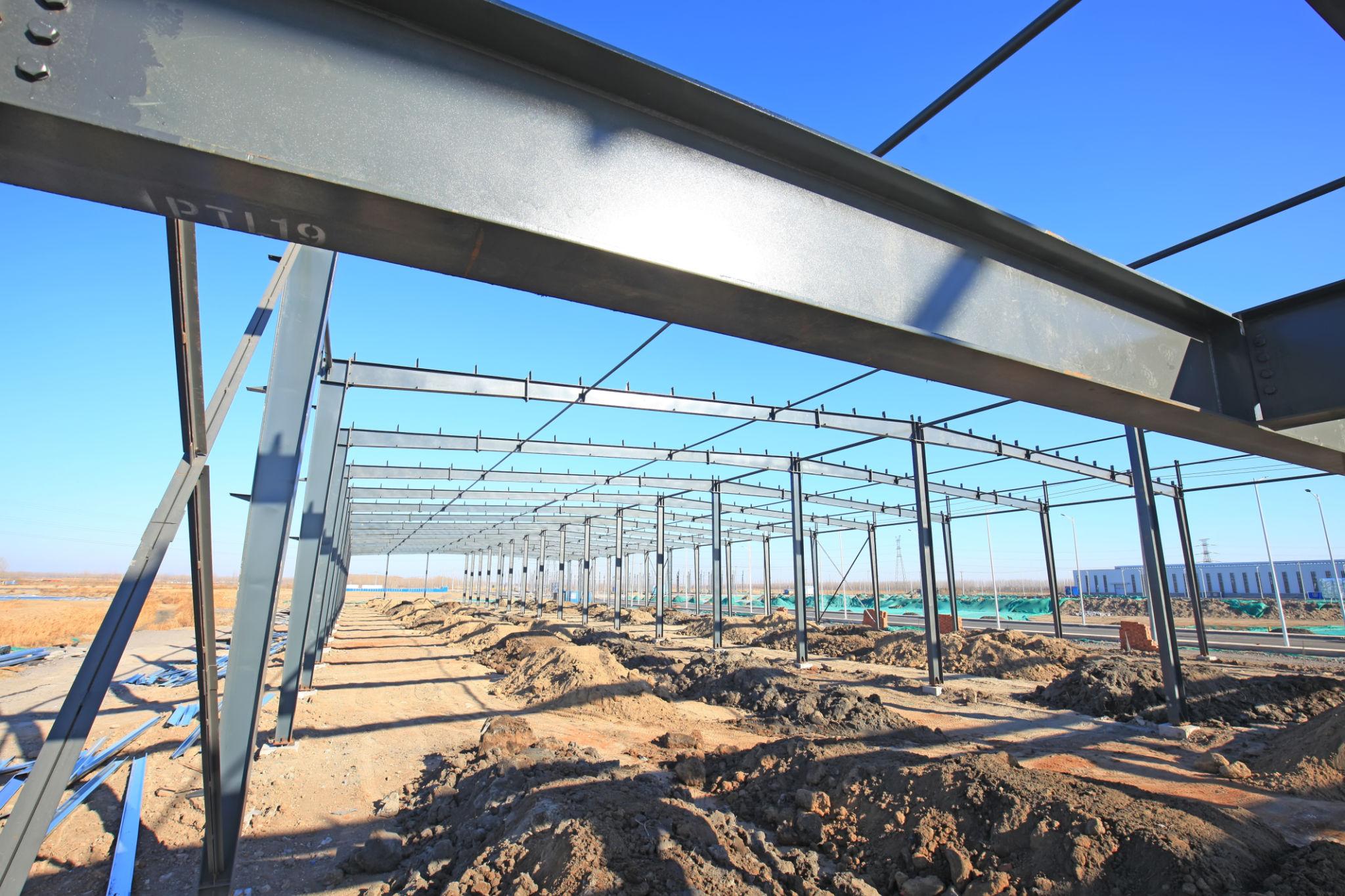 Large-scale industrial structure construction site with steel columns and crane installation