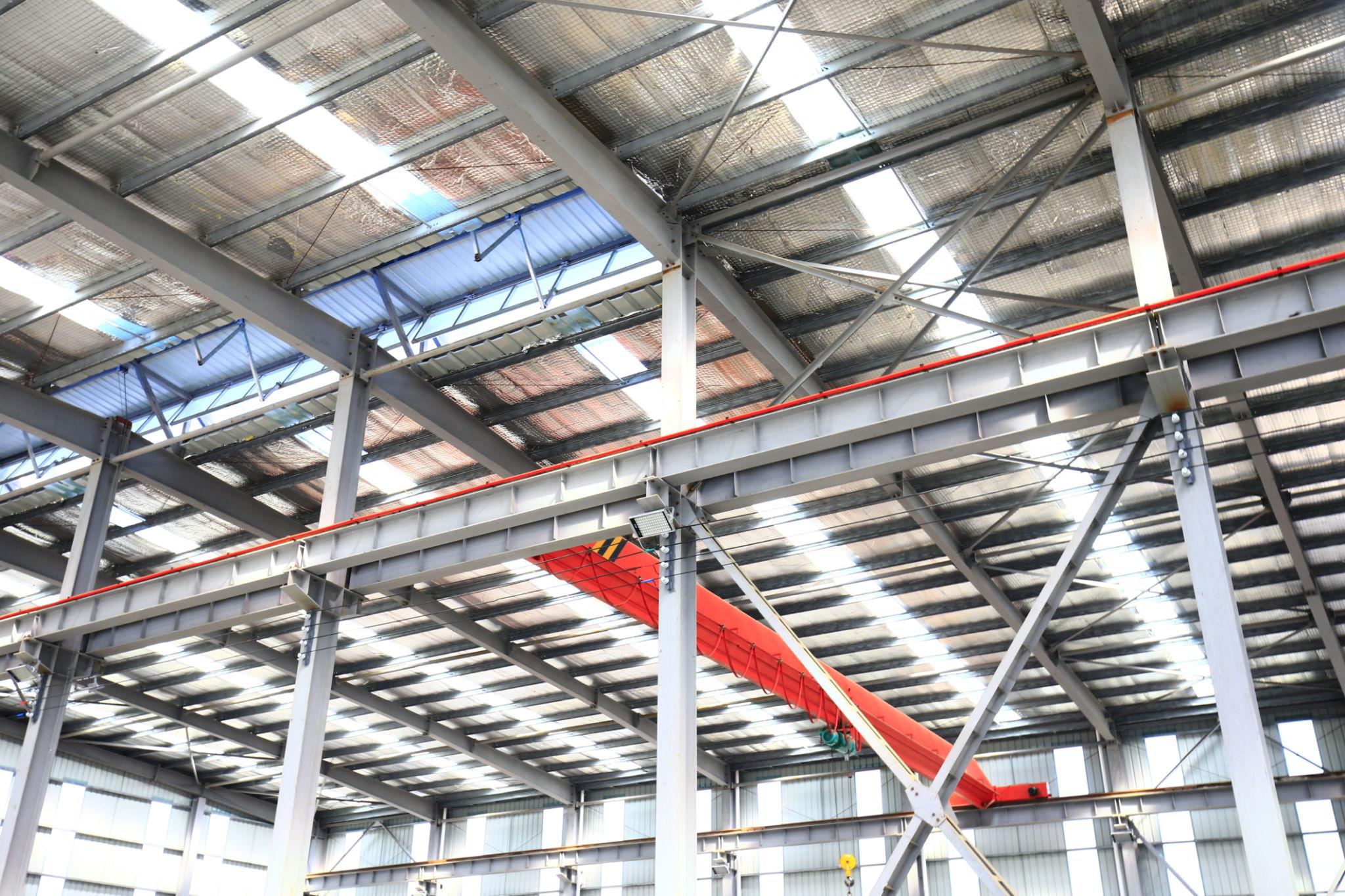 Pre-engineered industrial steel structure under installation with vertical columns and beam alignment